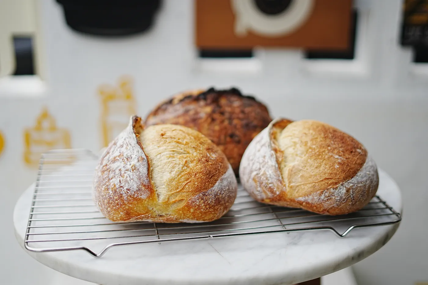 Two sourdough loaves cooling on a rack.