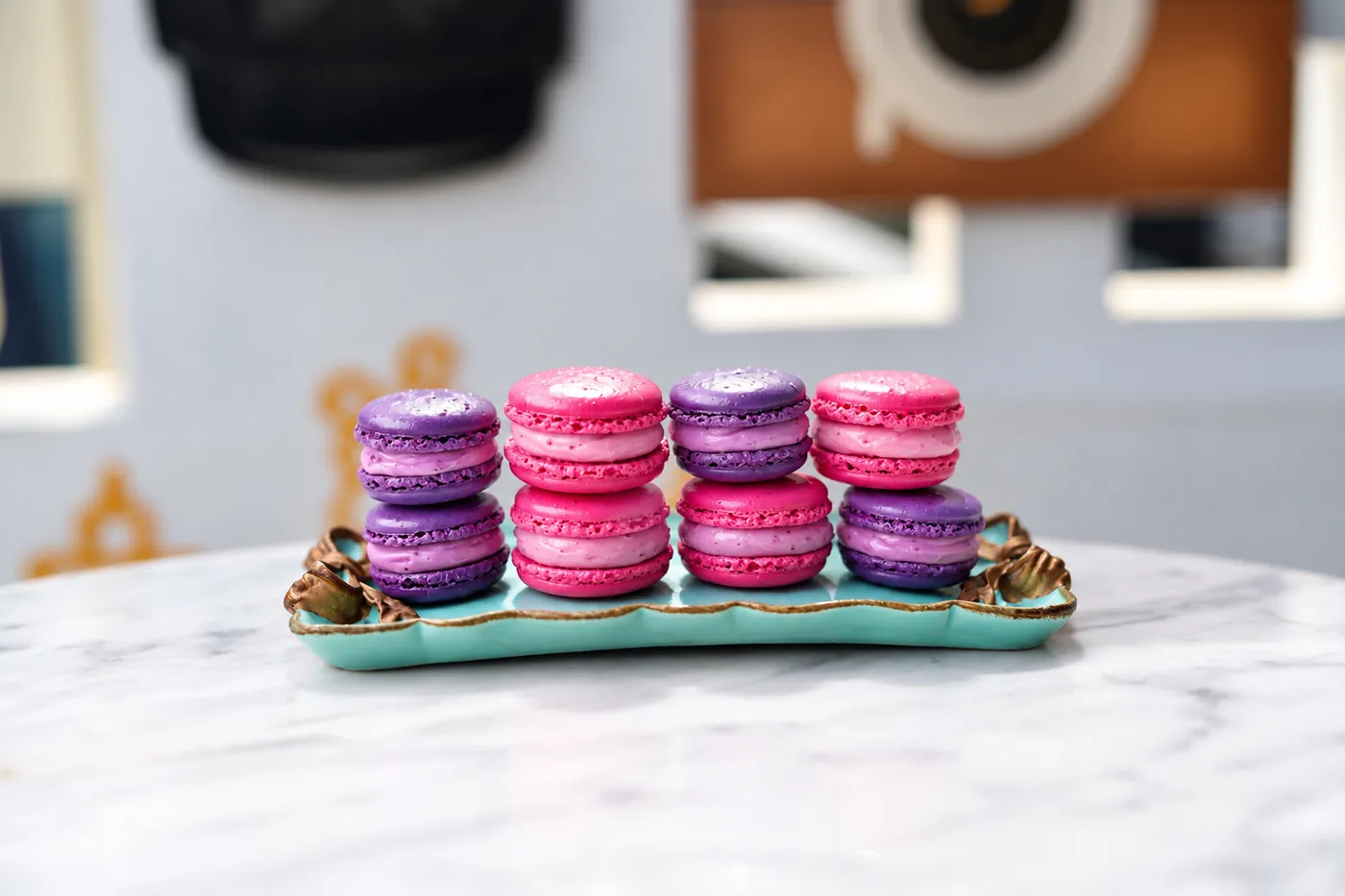 Macarons in pink and purple on a blue plate.