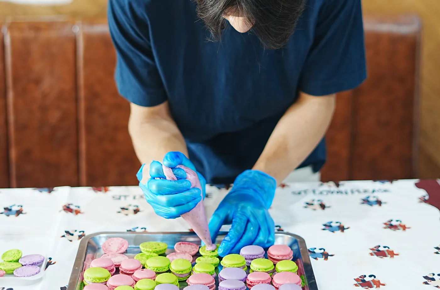A student filling a tray of pastel macarons.