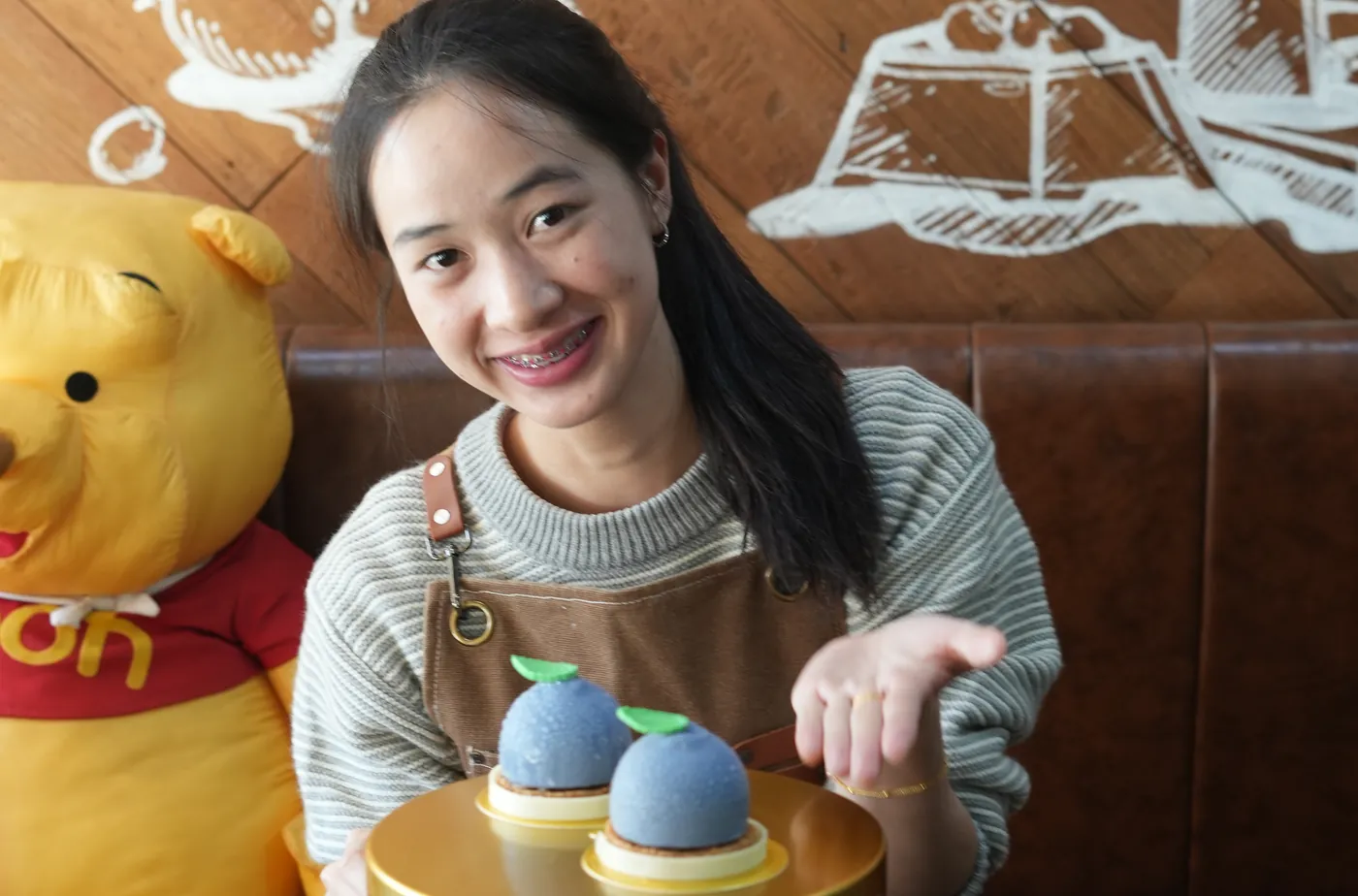 A student smiling behind the blueberry mousse cakes she made in class.