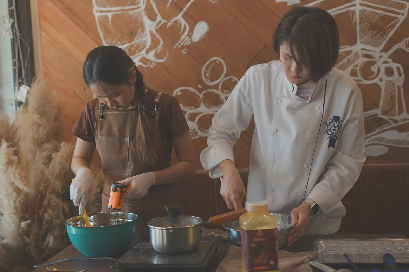 The pastry chef and a student cooking side by side.