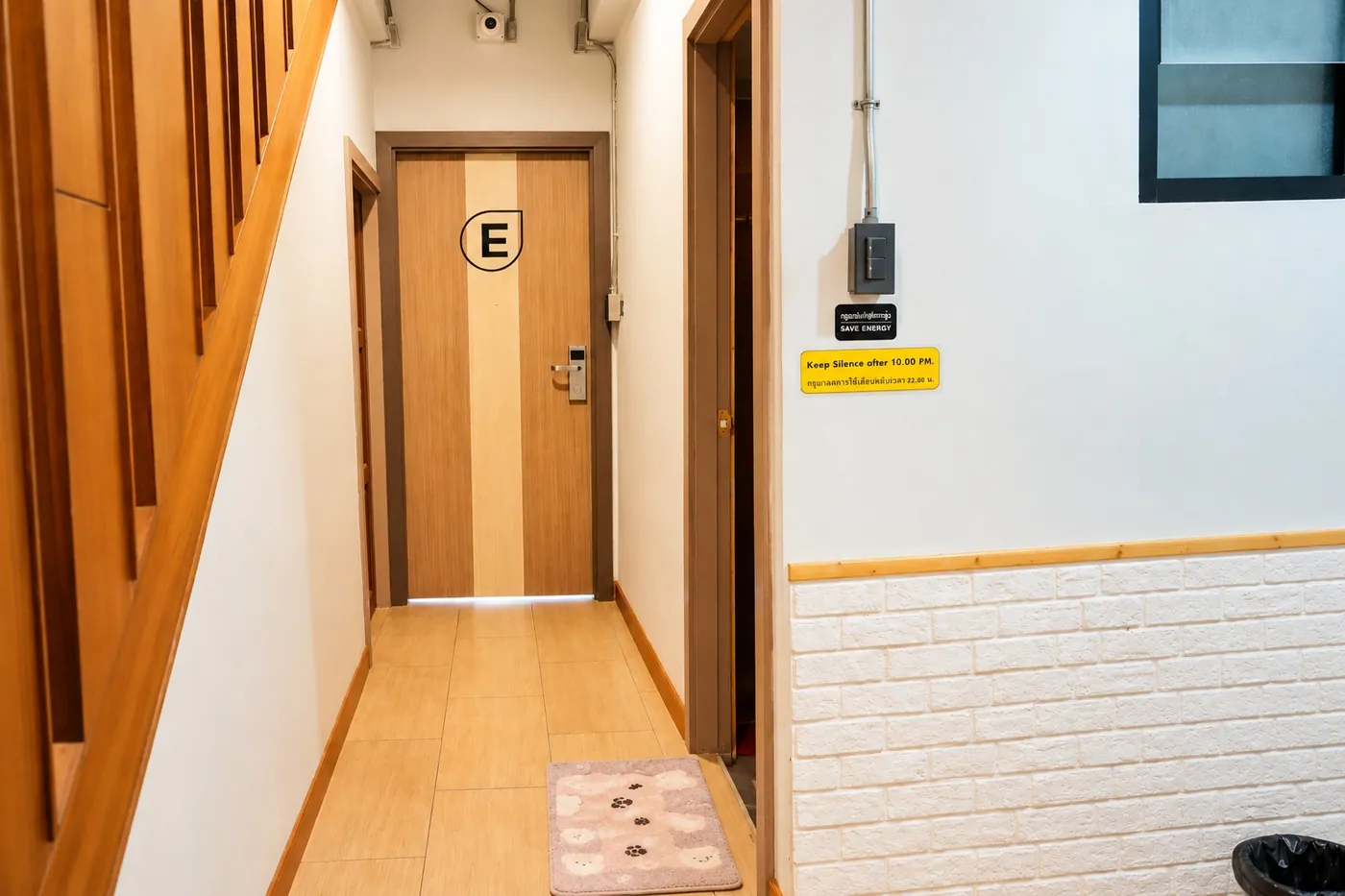 The hallway to room E, wooden doors and a white brick wall.