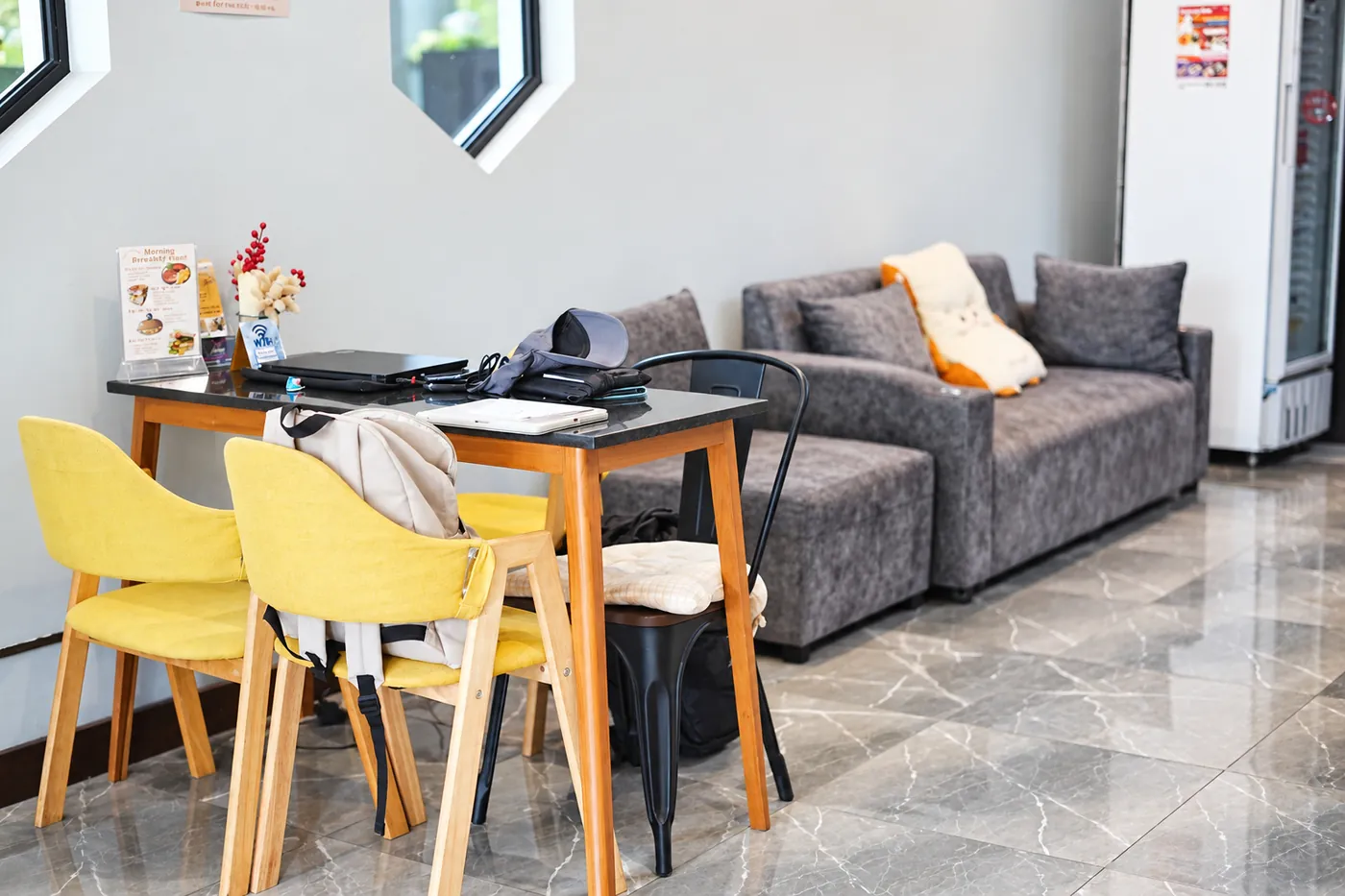 The lounge downstairs: a grey sofa, yellow chairs and a table by the window.