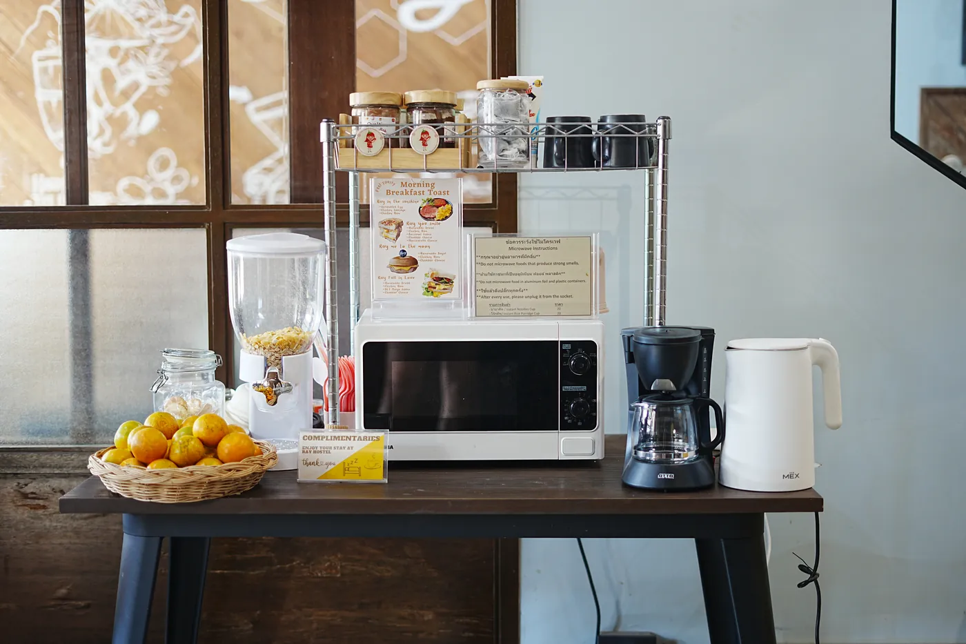 The refreshment corner: a microwave, a kettle, coffee, cereal and a basket of oranges.