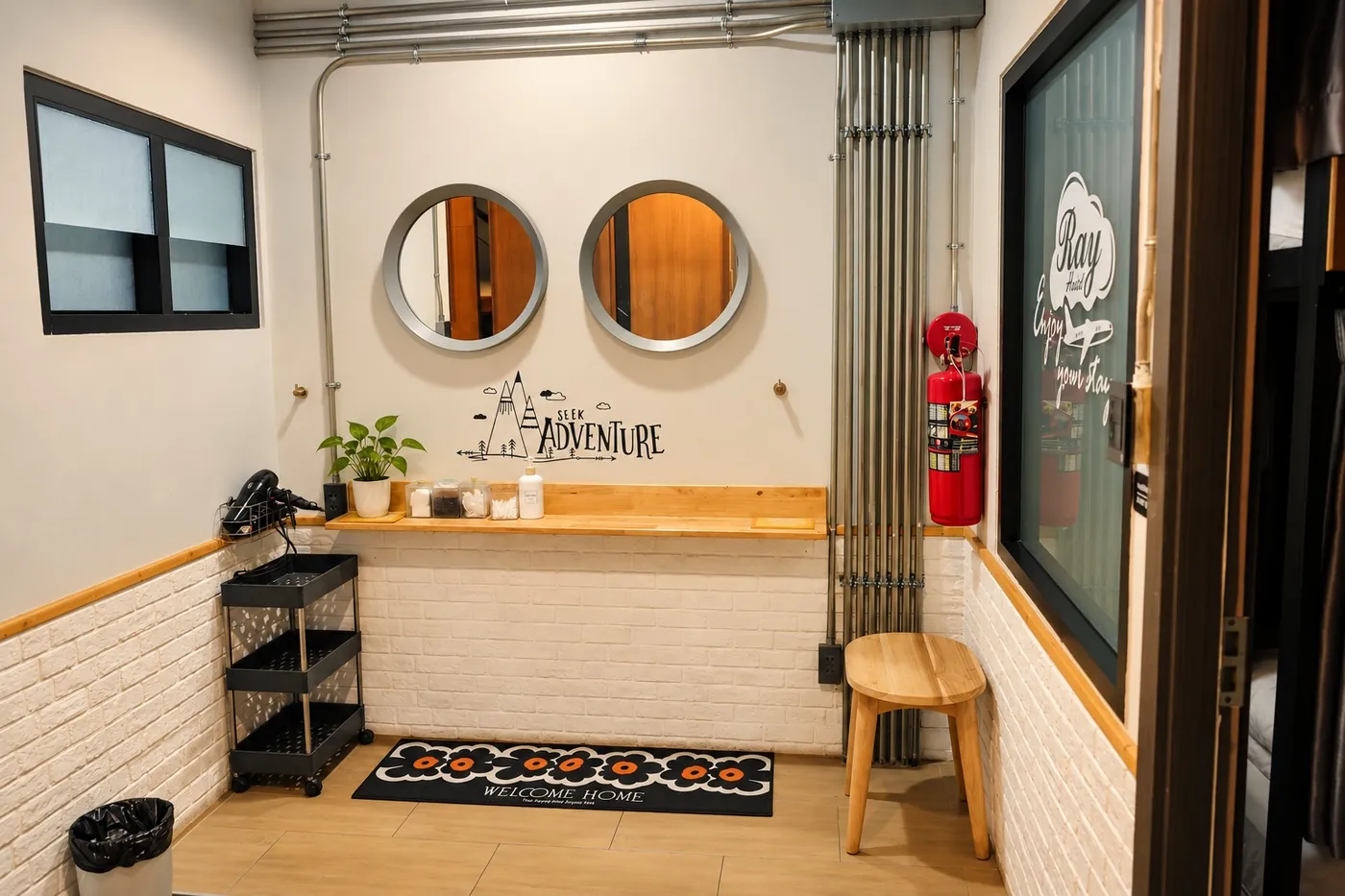 The vanity corner by the rooms, with a hairdryer, mirrors and a stool.