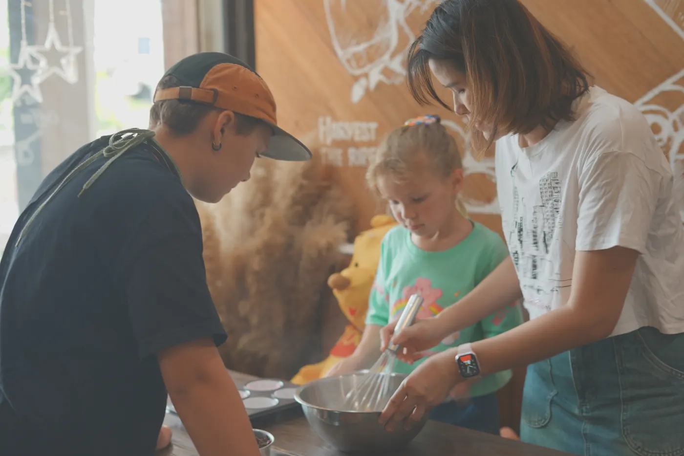 A teacher, a child and an adult whisking batter together in a baking class at Ray.
