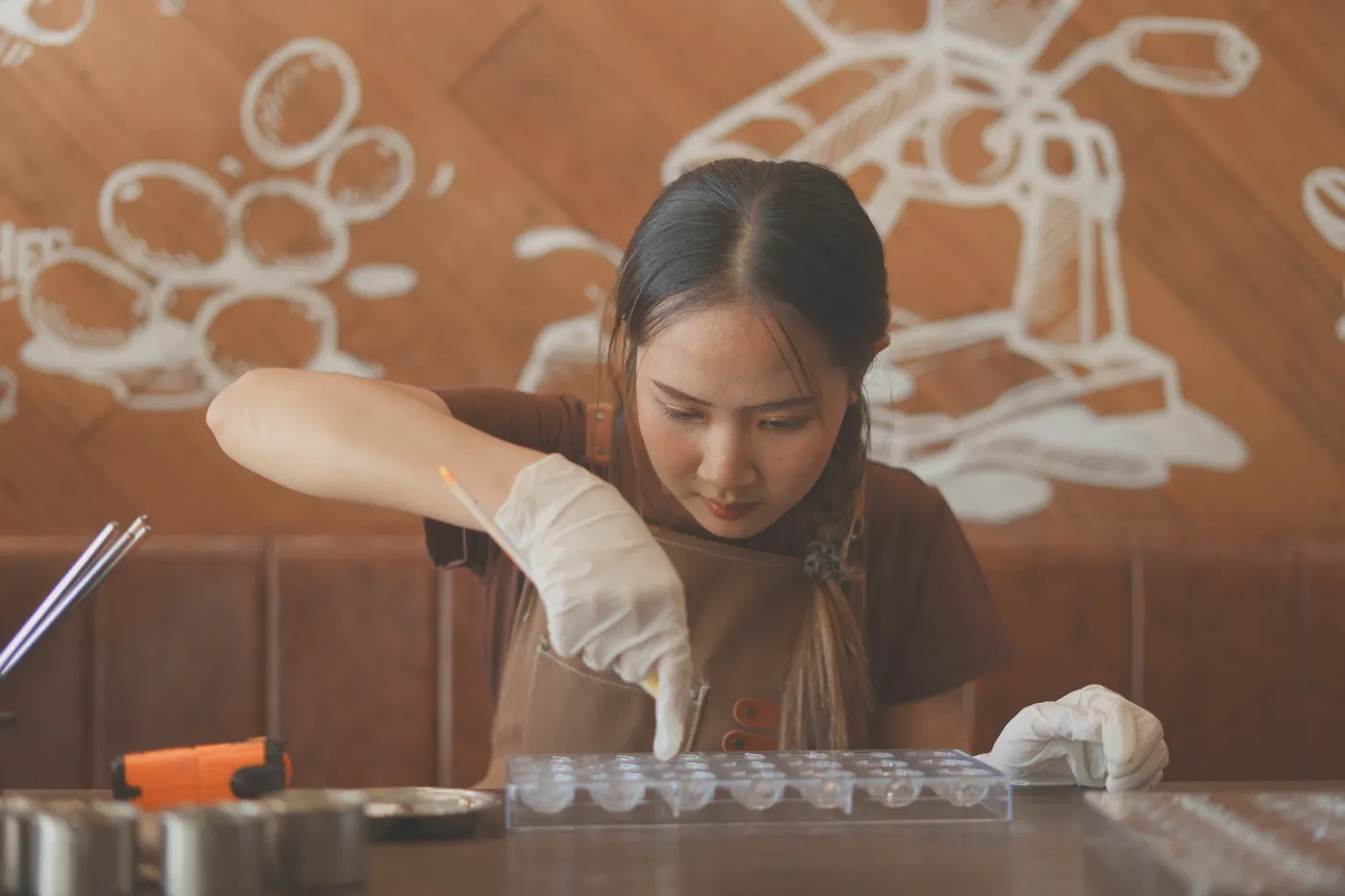 A baker filling chocolate moulds at the work table.