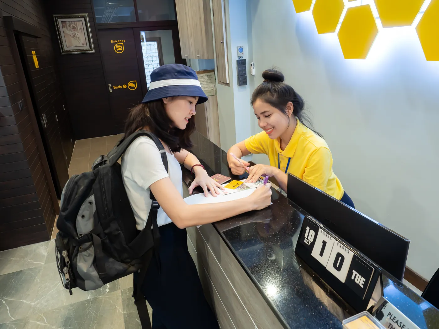 The receptionist smiling as she checks a guest in.
