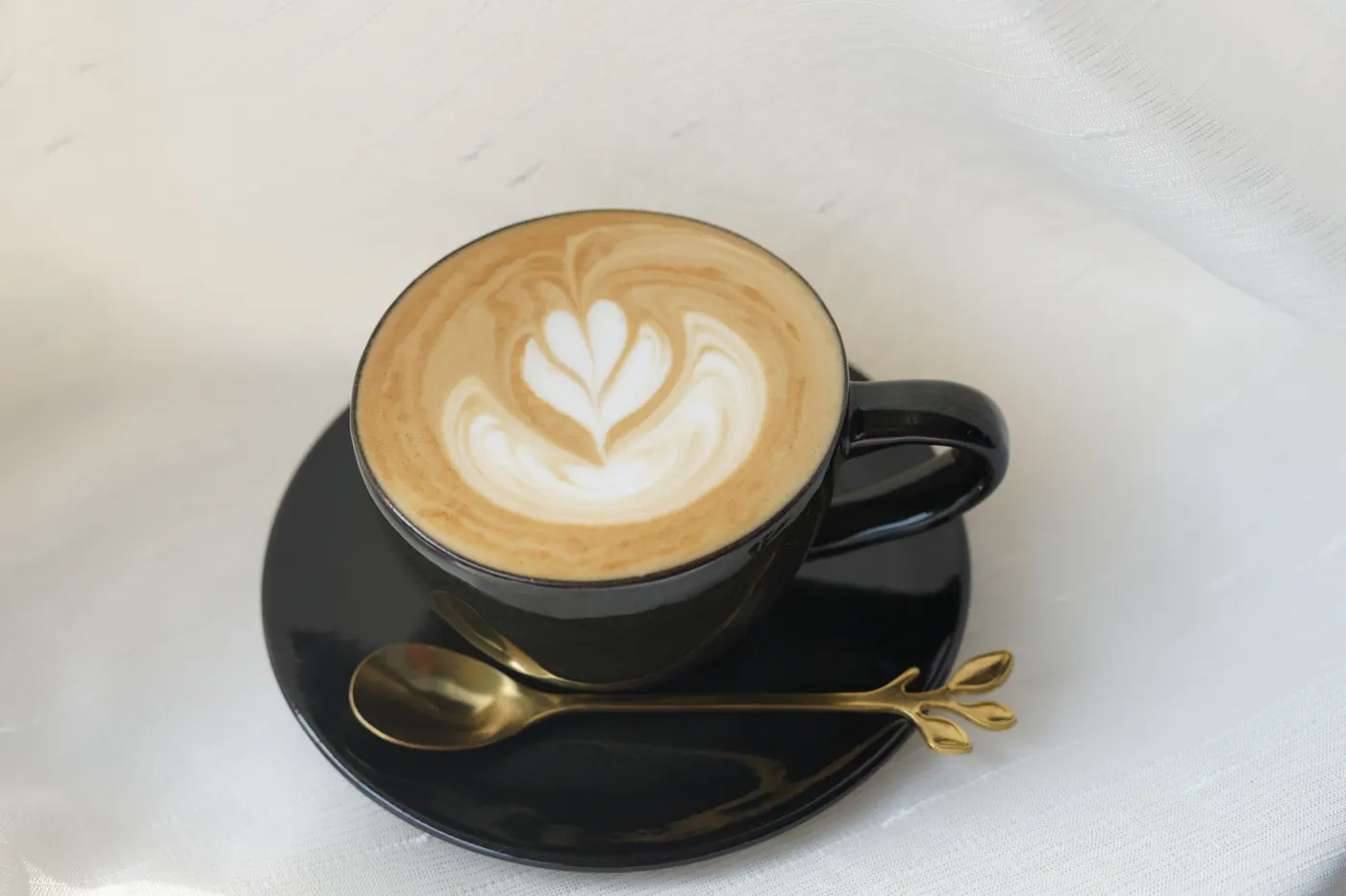 A latte with leaf art in a black cup at the coffee bar.
