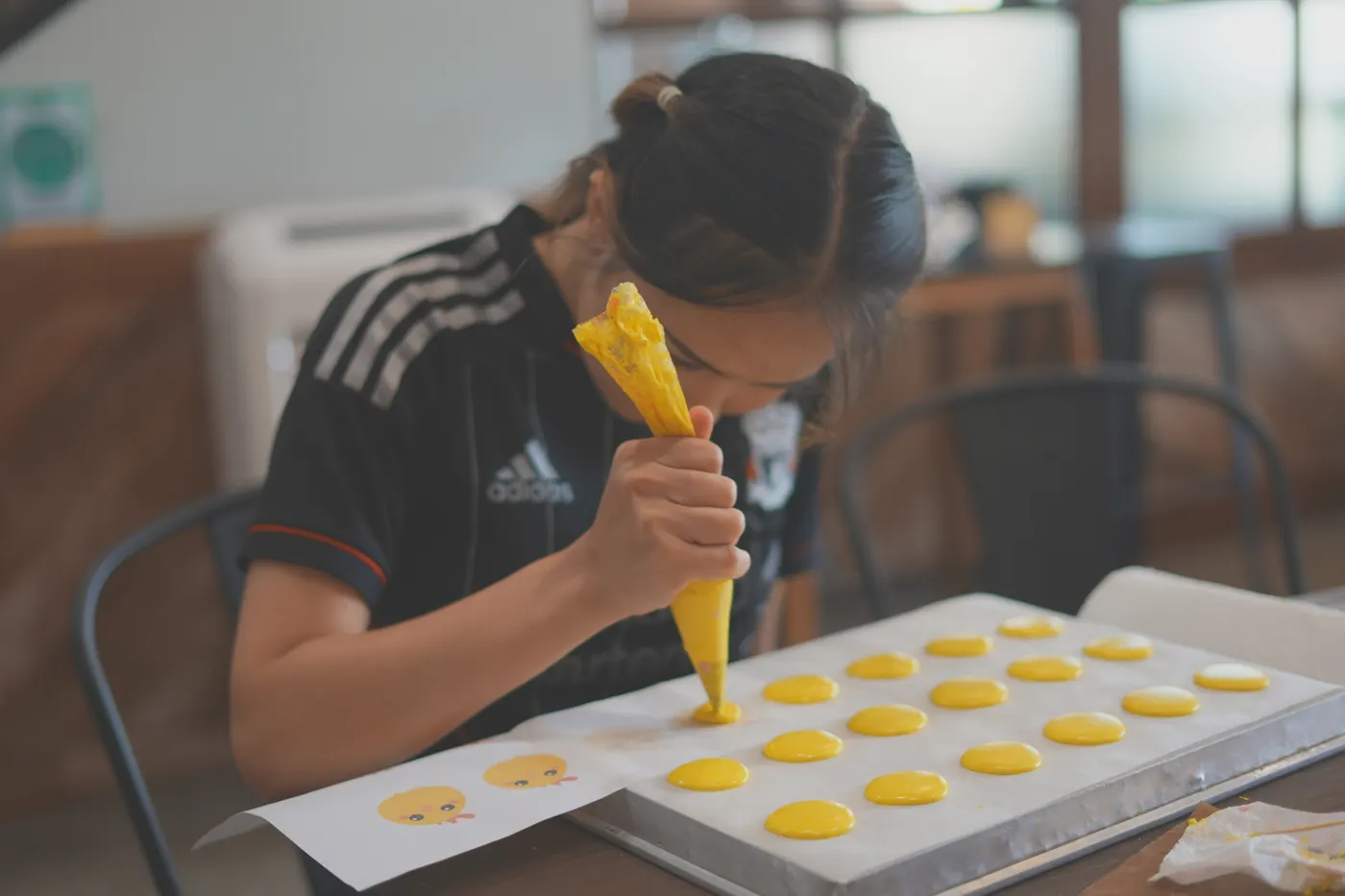 A student piping macaron batter onto a tray.