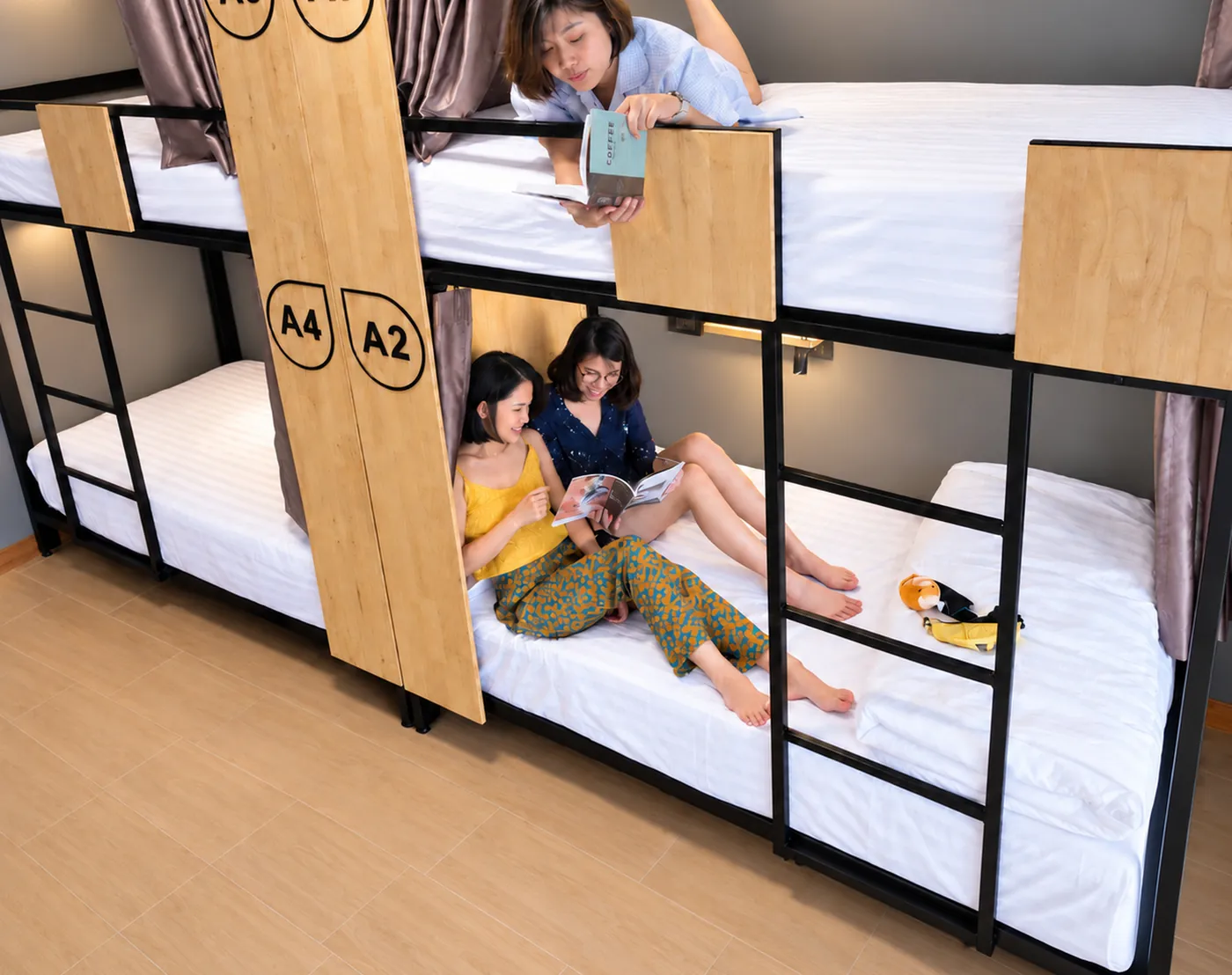 Three friends on the bunks of room A, laughing over a magazine.