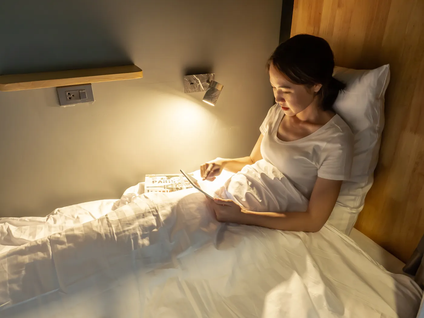 A guest reading on a tablet in bed at night.