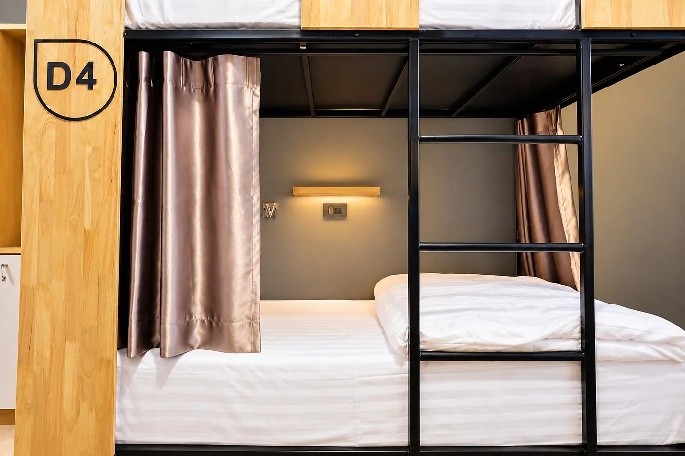 Bed D4 made up in white, its curtain drawn back and the reading light above.