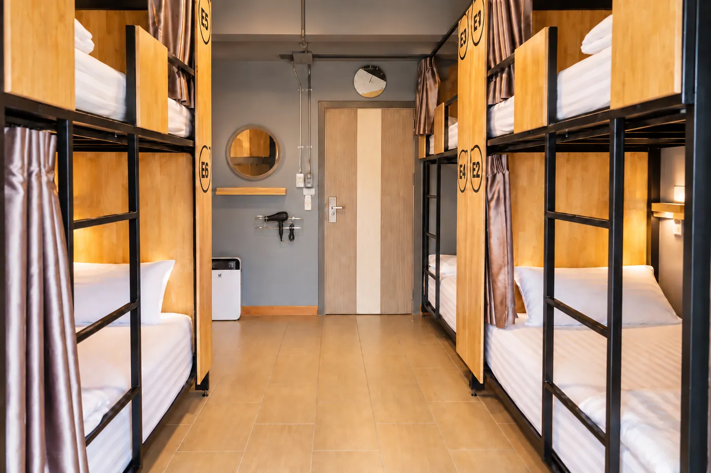 The aisle between the bunks of dorm E, the door at the far end.