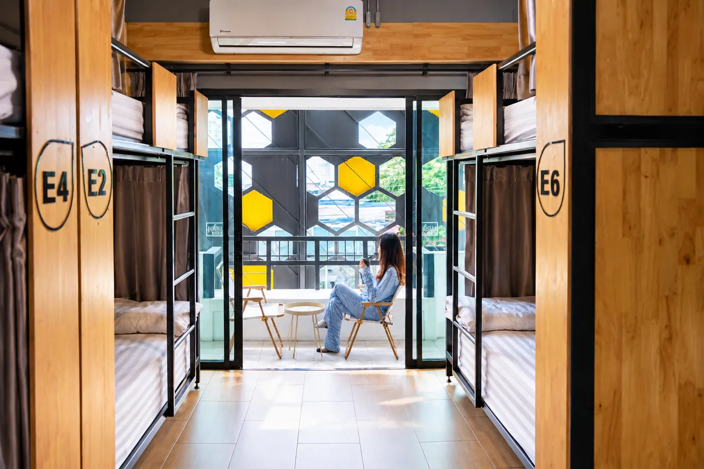 A guest reading on the balcony at the end of dorm E, behind the yellow hexagon screen.