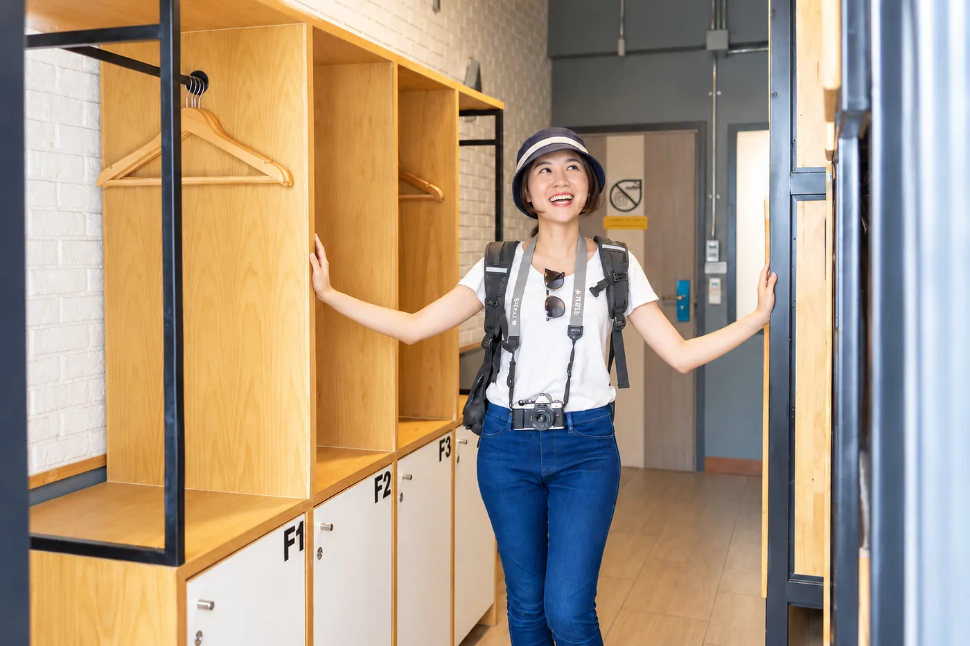 A guest with a camera and a backpack arriving at the wardrobe of room F.